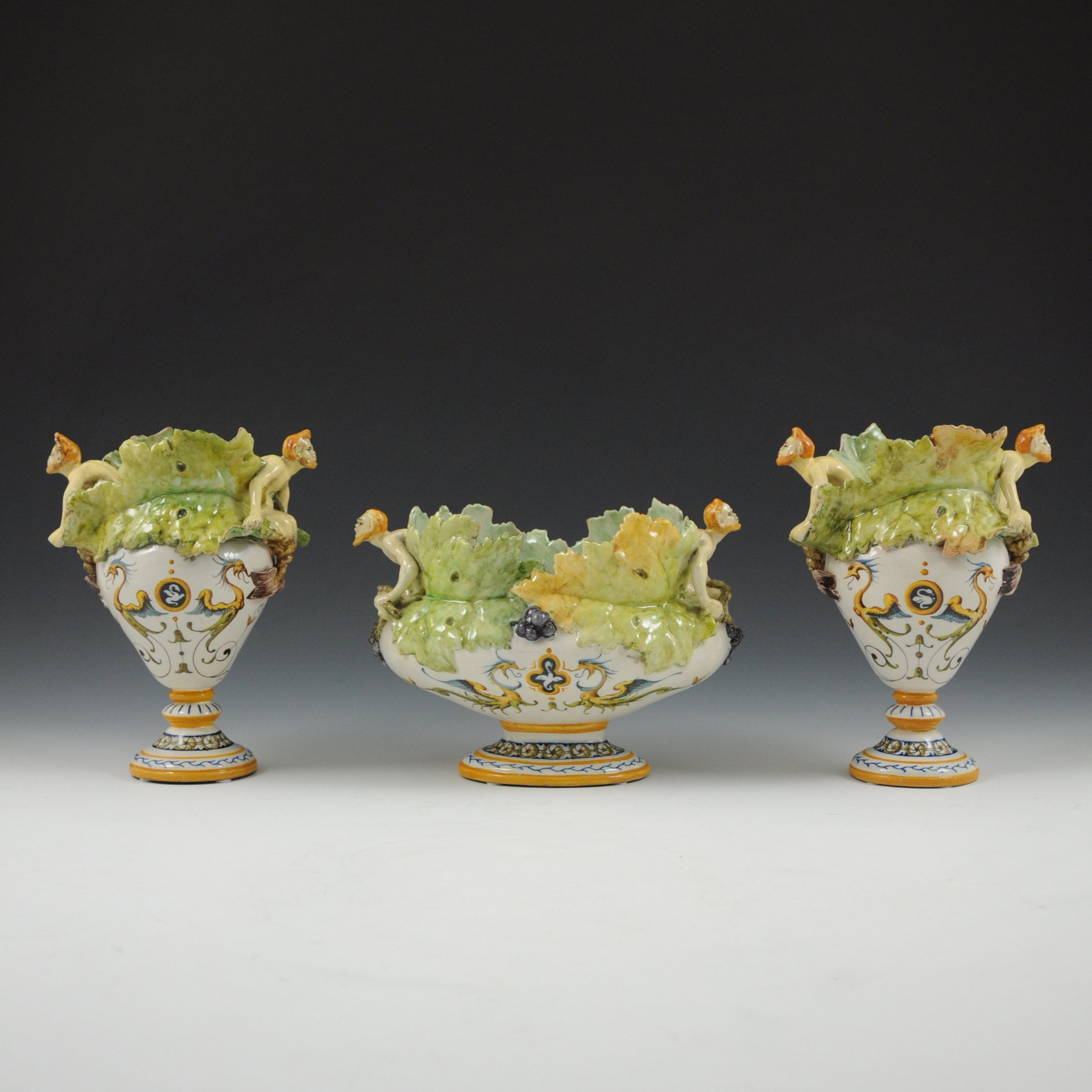 Triptyque composé d'une jardinière et d'une paire de vases ornés de feuilles de vigne et d'anses en forme de satyres.